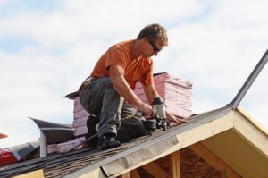 Close-up of metal flashing installed along a shingled roof edge near a brick chimney on a residential home.