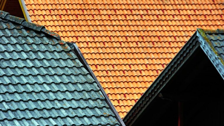 A residential house with one asphalt-shingle roof section and one standing-seam metal roof section after snowfall.